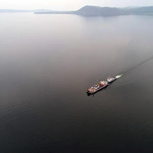 Aerial view shows a ferry transporting passengers and vehicles across the Yenisei