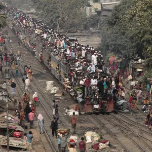 Commuters ride on the roof of a train as they come back to the city after attending