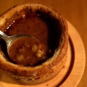 A customer eats a goulash soup from a bread bowl in a restaurant in Prague