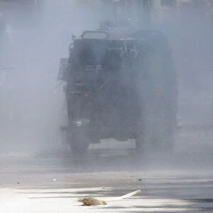 A dog jumps as riot police use a water cannon on a demonstrator during a protest against