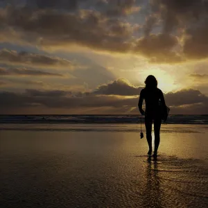 A female surfer walks out into the waves at Cardiff State Beach in Encinitas, California