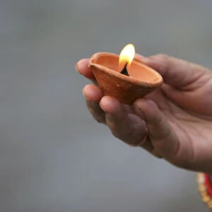 A Hindu devotee holds an earthen lamp as she offers prayers to the Sun god in Siliguri