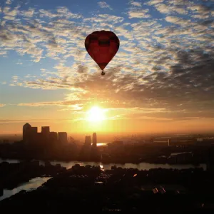 A hot air balloon rises into the early morning sky in front of the Canary Wharf financial