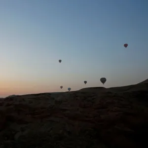 Hot-air balloons carrying tourists fly at sunrise over the city of Luxor