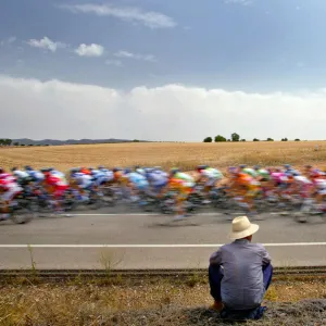 A man looks at a pack of riders cycle during the fifth stage of the Tour of Spain