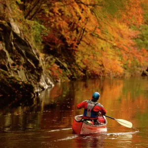 A man paddles his canoe down the river Garry near Killiekrankie, Scotland