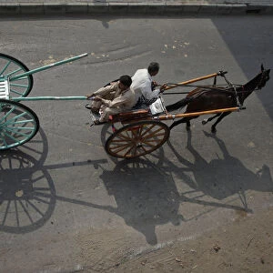 A man pulls a newly purchased cart while travelling in another horse-cart through