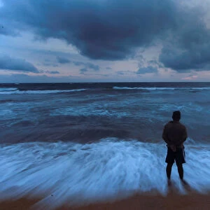 A man stands on a beach before the rain during the monsoon season in Colombo
