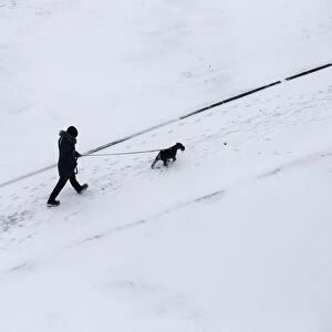 Man walks with a dog after snowfall in Minsk