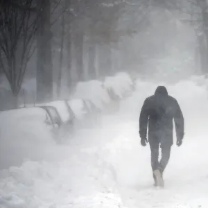 A man walks along a street covered by snow during a winter storm in Washington