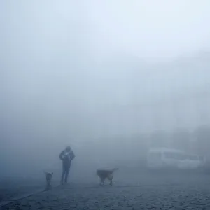 A man walks on a street on a foggy day in Sighnaghi