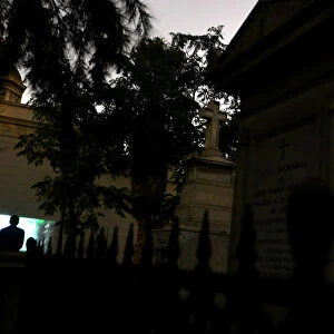 A man watches a movie in a cemetery as part of Ghost Tour heritage circuit, in Santiago