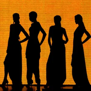 Models are silhouetted as they wear creations at a fashion show