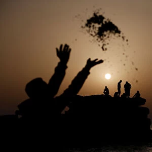 Palestinian throws sand during sunset, at the seaport of Gaza City