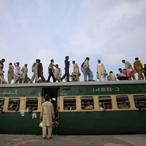 Passengers climb aboard a carriage of a train at a railway station in Lahore