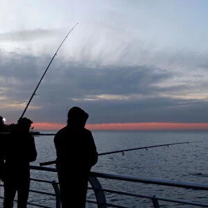 People are seen fishing ar the seaside during sunset in Beirut