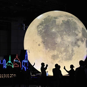People stand in front of a moon installation at Nanjing Road on the eve of the Mid-Autumn
