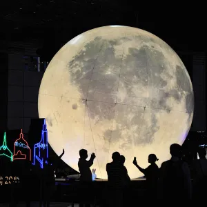 People stand in front of a moon installation at Nanjing Road on the eve of the Mid-Autumn