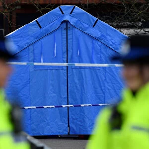Police officers stand guard in front of a forensics tent in a cordoned off area in the