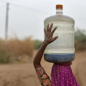 Village woman carries container filled with drinking water supplied by the government-run