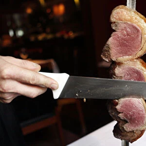 A waiter cuts a slice of Picanha meat at the Fogo de Chao Brazilian steakhouse in