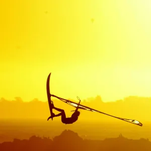 WINDSURFERS GETS AIRBOURNE AS THE SUN SETS ON CAPE TOWNs BLaUWBERG BEACH