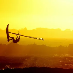 WINDSURFERS GETS AIRBOURNE AS THE SUN SETS ON CAPE TOWNs BLaUBERG BEACH