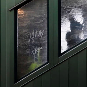 A woman is seen in silhouette through an ice covered window of a subway staircase in