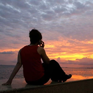 A woman watches the sunset at the Summit of the Americas in Trinidad