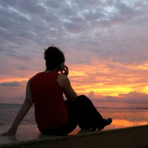 A woman watches the sunset at the Summit of the Americas in Trinidad