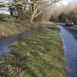 Flooded ditch overflowing into road, Aldingbourne, near Bognor Regis, West Sussex, England, February 2014