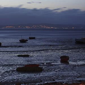 View of boats on intertidal mudflats habitat during low tide at night, looking towards Grange-over-sands in Cumbria