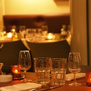 Interior of The restaurant Brunel at night. Tables with glasses, knives, ofrks, glasses