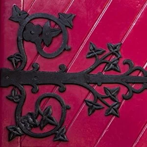 Ireland, Ennis. A decorative black hinge on a bright red door of the new Franciscan