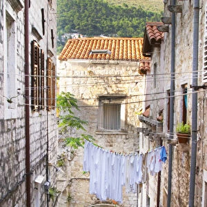A narrow street leading down with steep steps, clothes lines hanging across the street