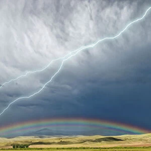 USA, Montana, Galen. Storm clouds with lightning and rainbow