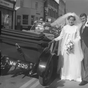 Bride and groom stood next to open top car