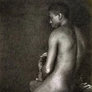 DAY: NUDE, c1897. Portrait of a nude man sitting on a leopard skin