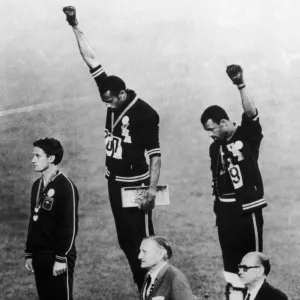 OLYMPIC GAMES, 1968. American runners Tommie Smith (center) and John Carlos (right) showing the Black Power salute during the medal ceremonies at the Olympic Games in Mexico City. Australian Peter Norman (left) wears an OPHR badge in solidarity. Photograph, 1968