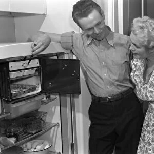 REPAIRMAN, 1942. A repairman inspecting a refrigerator. Photograph by Ann Rosener, 1942