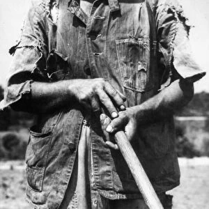 SHARECROPPER, 1936. A tenant farmer holding a hoe on a farm near Anniston, Alabama