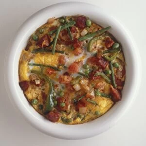 Bowl of Huevos a la Flamenca, eggs baked with tomatoes, green beans and peas, a typical dish from Southern Spain, view from above