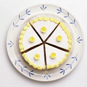 Cake cut into five slices, covered with white icing and yellow iced flowers, view