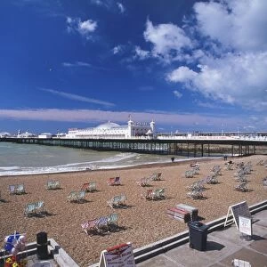 Great Britain, England, Brighton, view across sandy beach dotted with deckchairs towards Brighton Pier