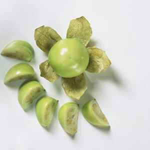 Whole green tomato and tomato slices, view from above