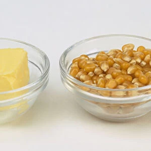 Ingredients to make popcorn, including butter, corn grains, cooking oil, in glass bowls
