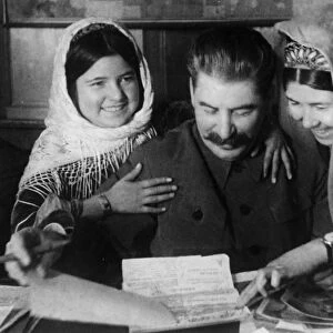 Joseph stalin with two young women from a collective farm in tadjikistan at a conference on cotton farming, january 1935