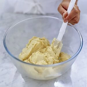 Mixing flour and butter together in glass mixing bowl using spatula