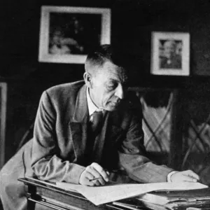 Russian composer, sergei v, rachmaninov, looking over a manuscript at his piano in the late 1920s