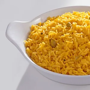 Saffron basmati rice with cardamom pods in serving dish, close-up